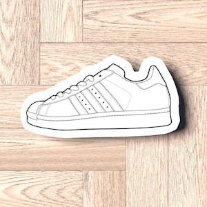 Peut inclure: Un dessin au trait noir et blanc d'une chaussure classique avec une semelle en caoutchouc et trois bandes sur le côté.