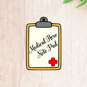 May include: A yellow and black clipboard with the text "Medical Hero Note Pad" and a red cross symbol.