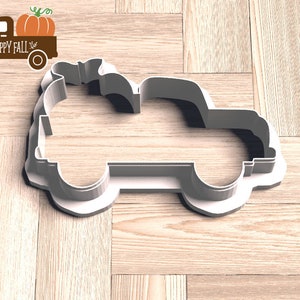 Pu&ograve; includere: Un tagliabiscotti in plastica bianca a forma di camioncino con una zucca nel cassone. Accanto, una grafica marrone di un camion con una zucca e le parole "HAPPY FALL".