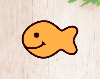 May include: A cartoon-style orange fish with a black outline and a smiling face. The fish is on a light wood background.