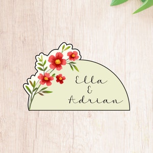 May include: A light green half-circle with a floral design and the text "Ella & Adrian" in black cursive.