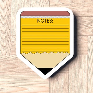 May include: A yellow pencil-shaped notepad with a red eraser and lined paper. The notepad says "NOTES:" at the top.