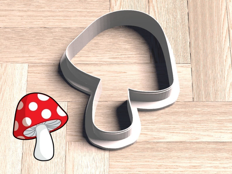 May include: White plastic mushroom cookie cutter on a wood background. A red and white mushroom illustration is also shown.