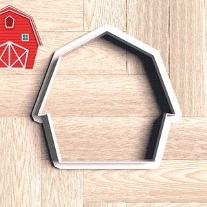May include: White plastic barn-shaped cookie cutter on a wood background.