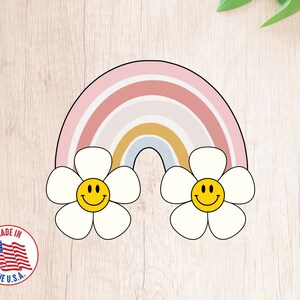 May include: A rainbow-colored arch with two white flowers on either side. Each flower has a yellow smiley face in the center.