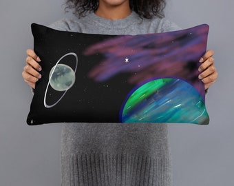 May include: A decorative pillow with a space-themed design. The pillow features a dark blue background with a green and blue planet, a smaller gray planet with a ring, and a white star. The design is reminiscent of a galaxy.
