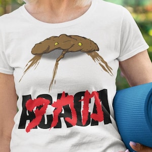 Puede incluir: Camiseta blanca con una imagen de dibujos animados de una caca marrón con ojos y un texto rojo "AGAIN".