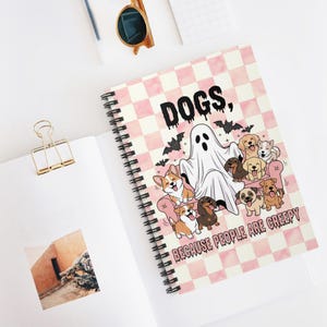 May include: A spiral-bound notebook with a pink and white checkered cover featuring a ghost sitting on a pink sofa surrounded by various dog breeds and bats. The text reads: DOGS, BECAUSE PEOPLE ARE CREEPY. The design includes cartoon illustrations.