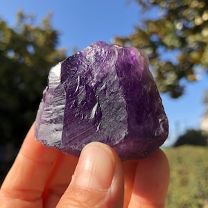 May include: A large, deep purple amethyst crystal with natural facets and a rough, textured surface.
