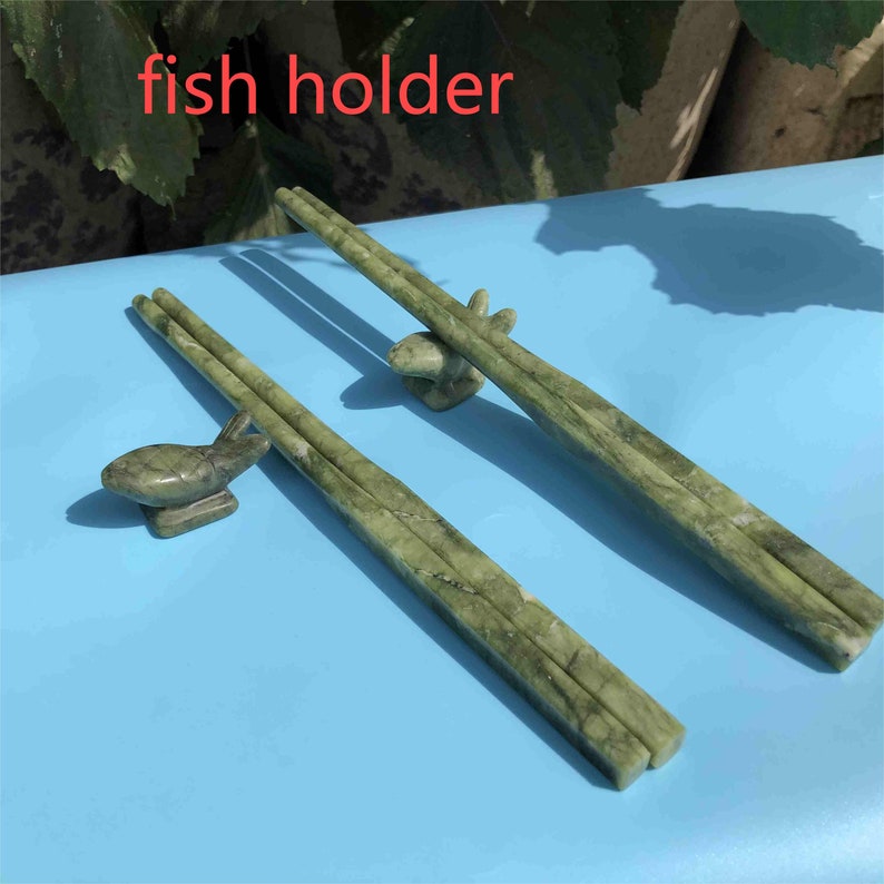 Op de afbeelding: Groene marmeren eetstokjes met bijpassende visvormige eetstokjessteunen. De eetstokjes en steunen hebben een natuurlijk, geaderd patroon. De tekst "fish holder" is zichtbaar.
