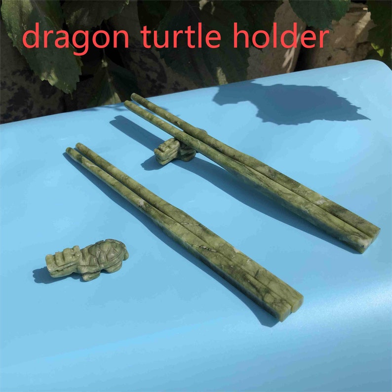 Op de afbeelding: Groene stenen eetstokjes met een bijpassende draak-schildpadhouder. De eetstokjes rusten op een draak-schildpadhouder. De tekst "dragon turtle holder" staat in de afbeelding.