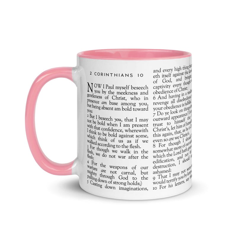 May include: White ceramic mug with a pink interior and handle. The mug features text from 2 Corinthians 10. A perfect gift for anyone who enjoys reading the Bible or needs a daily reminder of faith.