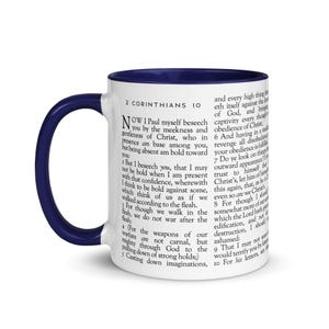 May include: White ceramic mug with a navy blue interior and handle. The mug features text from 2 Corinthians 10. The text is printed in black and covers the majority of the mug's surface.