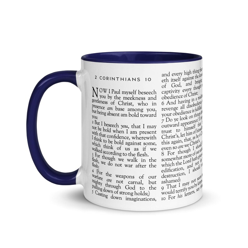 May include: White ceramic mug with a navy blue interior and handle. The mug features text from 2 Corinthians 10. The text is printed in black and covers the majority of the mug's surface.