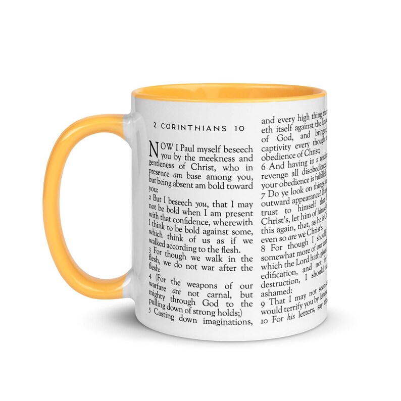 May include: White ceramic mug with a yellow handle and interior. The mug features text from 2 Corinthians 10, printed in black. The mug is a standard size for coffee or tea.