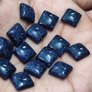 May include: A collection of 15 dark blue square-shaped gemstone cabochons with a sparkly, speckled texture.