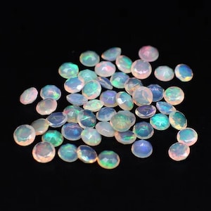 May include: A pile of iridescent white opal gemstones, each with a faceted round shape.