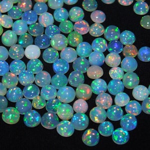 May include: A collection of round, iridescent opal cabochons in various shades of blue, green, and white. The opals have a shimmering, rainbow-like effect.