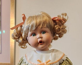 Adorable poupée de collection en porcelaine de style baby-doll avec tresses blondes bouclées vêtue d'une tenue de jeu verte portant un panier plein de chatons