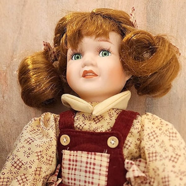 Cute Toddler Porcelain Collectible Doll with bright green  eyes, red hair in pigtails, wearing red corduroy jumpsuit and yellow blouse