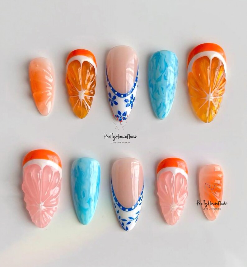May include: Set of ten false nails with various designs.  Some nails feature a blue and white floral design, while others have a 3D orange slice design.  The text "PrettyHouseNails Love Life Design" appears twice in the image.