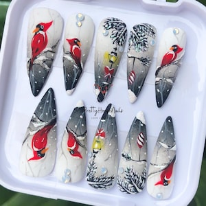 Lebhafter Kardinalvogel in der verschneiten Nachtpresse auf den Nägeln, Warme Weihnachten, langer Stiletto, künstlicher Nagel mit 3D-Kardinal, Schneeflocken, Feiertagsnägeln.