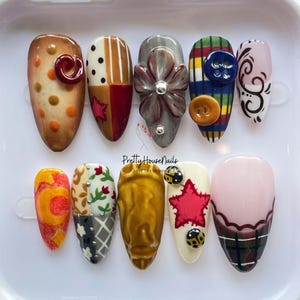 Peut inclure: Dix faux ongles aux motifs variés. Les ongles présentent des motifs à pois, patchwork, floraux et écossais, avec des embellissements tels que des boutons, une fleur et des coccinelles. La palette de couleurs comprend le marron, le rouge, le gris, le jaune et le rose.