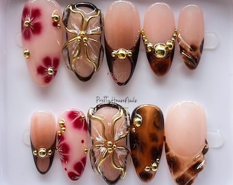 Uñas postizas de otoño, uñas almendradas medianas con flor 3D y dije dorado, juego de uñas carey en tonos neutros y marrones para los amantes del otoño.