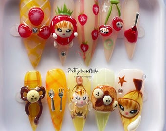 Puede incluir: Un conjunto de diez uñas acrílicas largas y puntiagudas con varios diseños 3D. Los diseños incluyen fresas, cerezas, lazos y personajes de dibujos animados. Las uñas están en una bandeja blanca. El texto "PrettyHouseNails LOVE LIFE DESIGN" es visible.