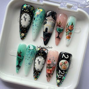 May include: A set of ten long, almond-shaped artificial nails with various designs. The designs include clocks, floral patterns, and a Japanese-style building. The nails are painted in a variety of colors, including black, white, pink, and green.