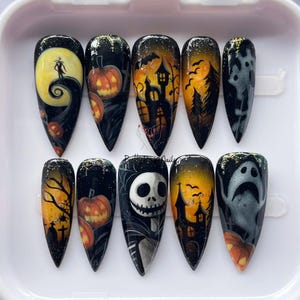 May include: A set of ten long, pointed acrylic nails with Halloween designs. Each nail features a different spooky scene, including pumpkins, haunted houses, and characters from The Nightmare Before Christmas, set against a dark background.