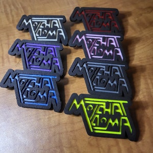 May include: Seven different colored, laser-cut wood patches with the text "MOCHATOMA" in a stylized font. The patches are in the colors white, pink, purple, gray, blue, green, and black.