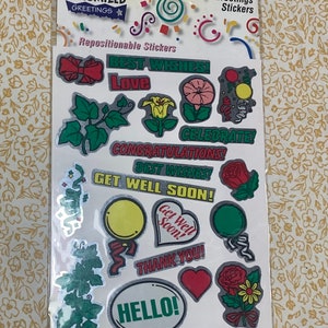 May include: A sheet of repositionable stickers with various greetings. Designs include flowers, bows, balloons, and phrases like "Best Wishes," "Love," and "Hello." The stickers are in various colors, including red, green, yellow, and pink.