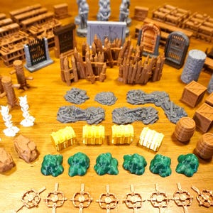 Puede incluir: Colección de piezas de terreno en miniatura para juegos de mesa. Incluye varias estructuras como muros, puertas, barriles, cajas y formaciones rocosas en tonos marrón, gris, amarillo y verde. Ideal para crear entornos de juego inmersivos.