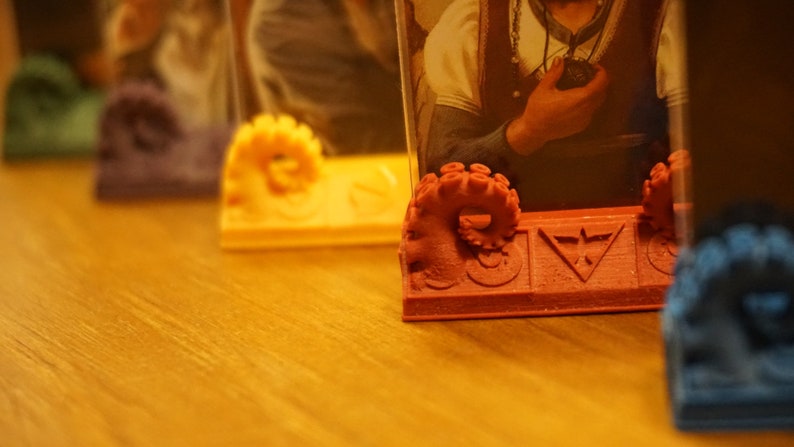 Pode incluir: Um conjunto de quatro suportes para cartas impressos em 3D, cada um com uma cor diferente e um design de polvo. Os suportes s&atilde;o feitos de um material liso, semelhante ao pl&aacute;stico, e s&atilde;o projetados para conter cartas de jogo de tamanho padr&atilde;o.
