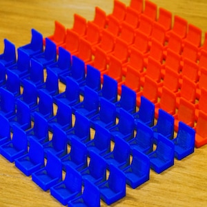 Puede incluir: Primer plano de una gran cantidad de piezas de juego de plástico azul y naranja dispuestas en filas. Las piezas son todas del mismo tamaño y forma, y están dispuestas en un patrón escalonado.