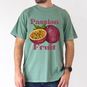 May include: A teal green t-shirt with a graphic of a passion fruit and the text "Passion Fruit" in pink.
