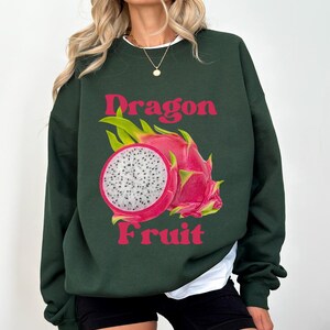 May include: A dark green sweatshirt with a pink and white dragon fruit graphic and the text "Dragon Fruit" in pink.