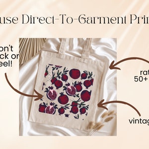 May include: A white tote bag with a red pomegranate print. The bag is made with direct-to-garment printing, which is rated for 50+ washes and has a vintage look.