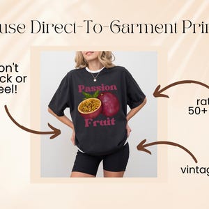 May include: A black t-shirt featuring a graphic of a passion fruit and the text "Passion Fruit". The shirt is being modelled by a person. The text "We use Direct-To-Garment Printing" is at the top of the image. The text "won't crack or peel!" is on the left side of the image. The text "rated for 50+ washes" is on the right side of the image. The text "vintage look" is at the bottom right of the image.