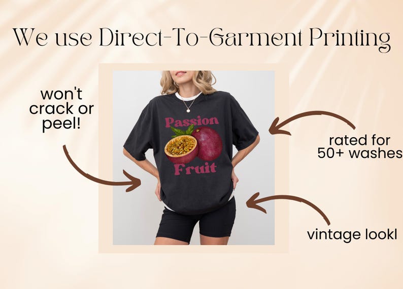 May include: A black t-shirt featuring a graphic of a passion fruit and the text "Passion Fruit". The shirt is being modelled by a person. The text "We use Direct-To-Garment Printing" is at the top of the image. The text "won't crack or peel!" is on the left side of the image. The text "rated for 50+ washes" is on the right side of the image. The text "vintage look" is at the bottom right of the image.