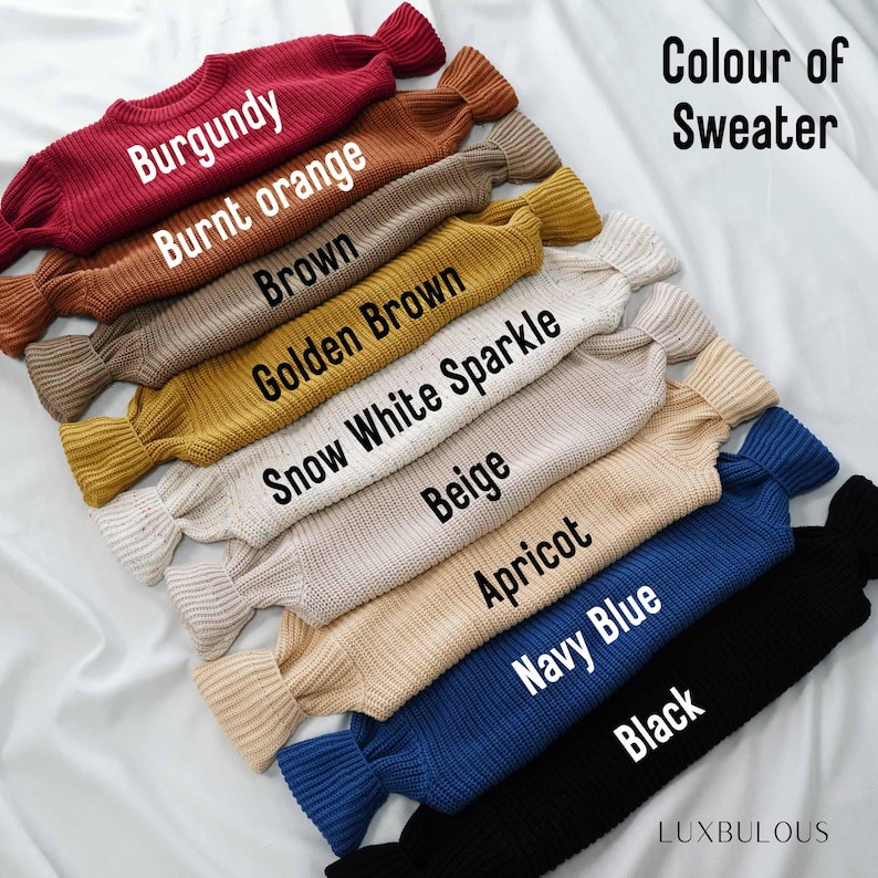 May include: A stack of ten sweaters in different colors, including burgundy, burnt orange, brown, golden brown, snow white sparkle, beige, apricot, navy blue, and black. The sweaters are arranged from darkest to lightest, with the burgundy sweater on top and the black sweater on the bottom. The text "Colour of Sweater" is written in white letters on a black background at the top of the image.