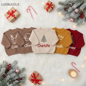 May include: Five children's Christmas sweaters in brown, beige, and red, each with a different design: a reindeer, a Santa hat, a Christmas tree, a crown, and a Christmas tree. Each sweater has a name embroidered on it.