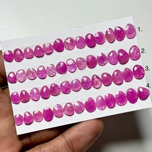 May include: Rows of oval-shaped, faceted pink gemstones are displayed on a white card. The gemstones vary in shade from light to deep pink. The card is labeled with numbers 1 through 4, indicating different gemstone strands.