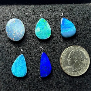 May include: Five polished opal gemstones in various shapes and colors, including blue, turquoise, and teal. A U.S. quarter coin is included for size comparison. The opals are numbered 1 through 5.
