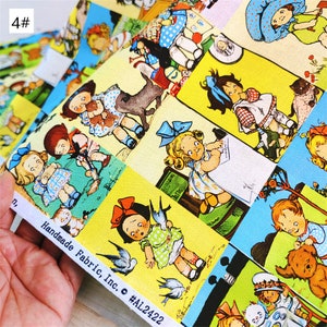 May include: A yellow fabric with a repeating pattern of children in various poses. The children are wearing colourful clothing and are surrounded by flowers and other objects. The fabric is labelled "Handmade Fabric, Inc. #AL2422".