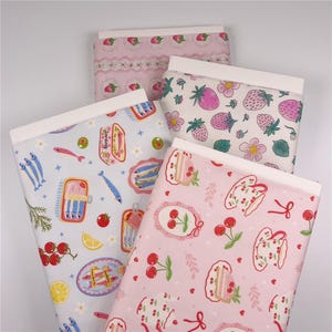 Può includere: Quattro rotoli di tessuto fantasia con bordi bianchi. I disegni includono fragole, sardine, ciliegie e motivi floreali in rosa, blu e bianco. Ideale per cucito e progetti di artigianato.