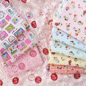 May include: A stack of colorful fabric featuring a variety of patterns, including gingham, polka dots, and floral designs. The fabric is decorated with images of girls in dresses and houses.