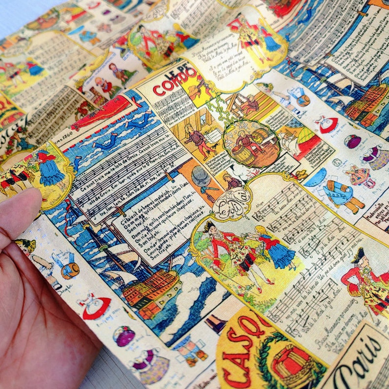 May include: A colorful fabric with a repeating pattern of illustrations and text. The fabric features a blue and white ship, a red and white building, and a musical score. The text includes the words "Le Petit Comtois" and "Casco Paris".