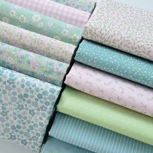 May include: A stack of 10 different patterned fabric squares in shades of pink, green, and blue. The fabrics feature floral, leaf, and geometric patterns.